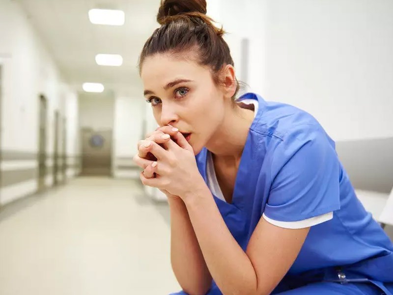 Woman in healthcare/medicine sitting in a hospital hallway setting contemplating changes in her career.